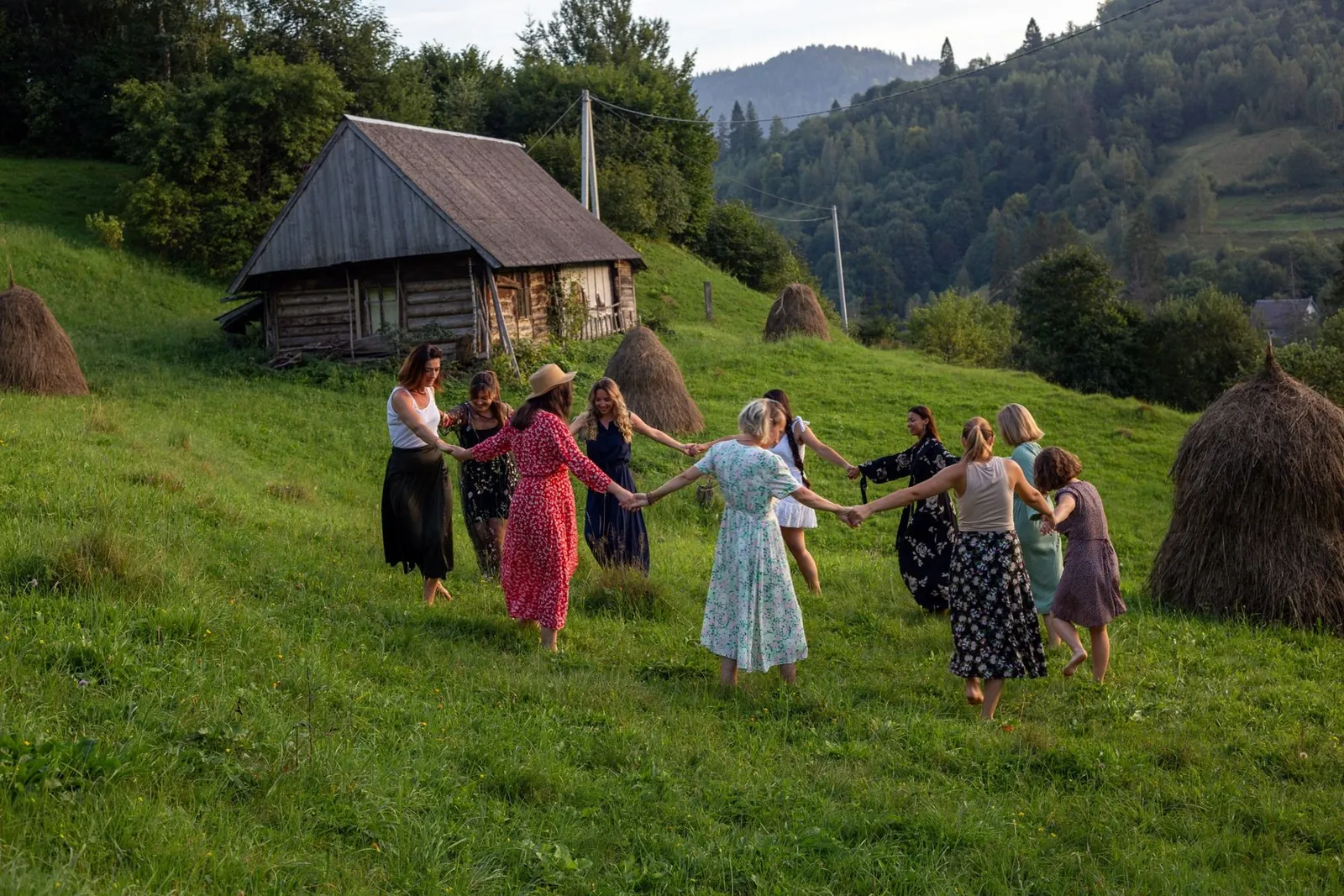 A circle of women holding hands on a mountain meadow