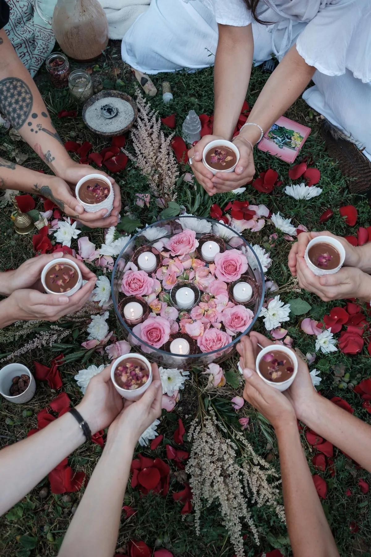 Hands holding cups of cacao in a circle